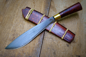 knife custom or Enep in the natural wood scabbard on old table background handmade of Thailand