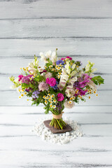 Beautiful bouquet of seasonal flowers on white wooden rustic background.