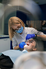 The dentist treats the patient's teeth. Puts braces on a girl. Dentist's office.