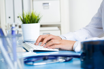 Close-up of doctor hands typing at keyboard