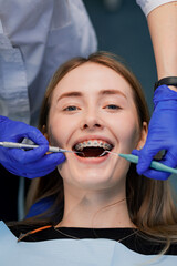 The dentist treats the patient's teeth. Puts braces on a girl. Dentist's office.
