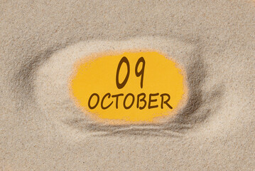 October 9. 9th day of the month, calendar date. Hole in sand. Yellow background is visible through hole. Autumn month, day of the year concept
