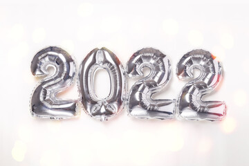 Silver balloons in the form of numbers 2022 on white background. New year celebration. Happy New Year 2022 concepts. Bokeh effect
