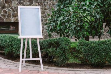 Wooden easel with blank canvas outdoos. Space for text