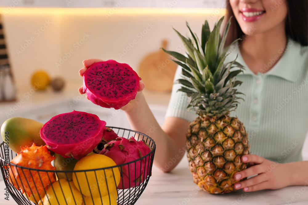 Sticker Young woman with fresh exotic fruits at table indoors, closeup