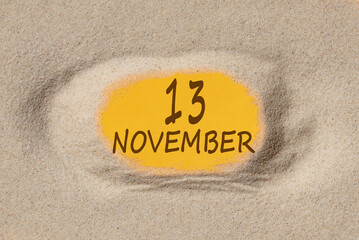 November 13. 13th day of the month, calendar date. Hole in sand. Yellow background is visible through hole. Autumn month, day of the year concept