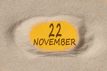 November 22. 22th day of the month, calendar date. Hole in sand. Yellow background is visible through hole. Autumn month, day of the year concept