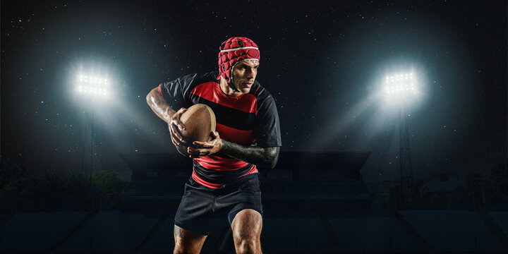 One caucasian man playing rugby on the stadium at stadium with flashlights. Cocept of sport, competition.