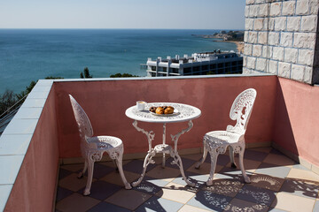 Chairs and a table standing on the veranda with stunning sea views. Coffee, cakes and biscuits on a plate. Bulgaria, Golden Sands