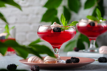 Fruit jelly with fresh mulberries in a glass bowl on a gray background