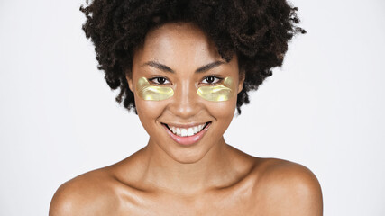 Smiling african american woman with golden eye patches isolated on grey