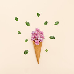 Waffle ice cream cone with pink small flowers and green leaves on millennial pink background.
