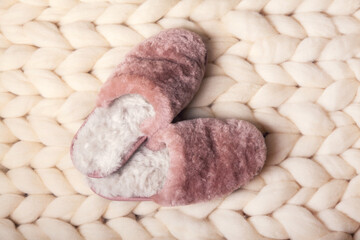 Home slippers made of fur on the background of white merino wool plaid. The atmosphere of...