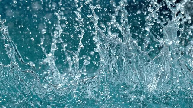 Super slow motion of splashing water isolated on blue background. Filmed on high speed cinema camera, 1000 fps.