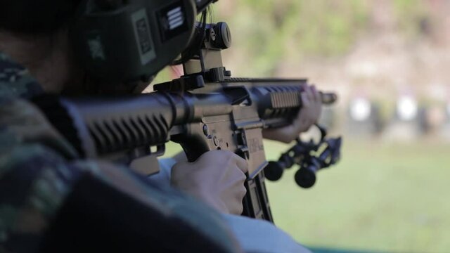 A girl shoot with assault rifle in outdoor arena