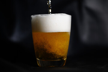 Glass of cold drink in yellow on black background