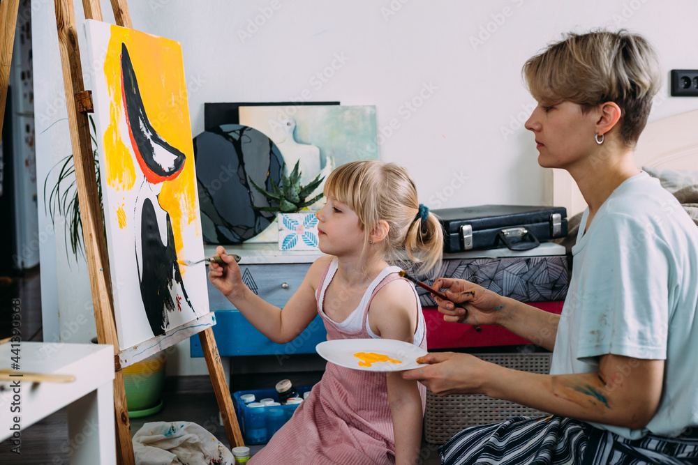 Wall mural beautiful mother artist and her child paint picture at home with acrylic paints.