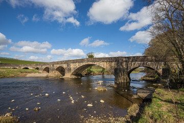 Fototapeta na wymiar Large stone bridge crossing the river ribble near Clitheroe. Edisford bridge with rocks in the foreground 