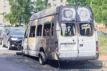 A burnt-out car on a city street, serious fire damage after a fire on the body of a passenger minibus