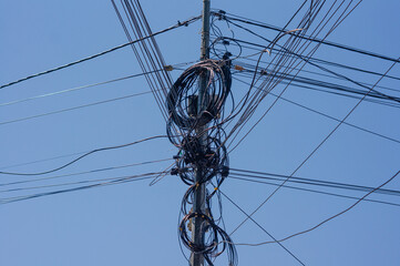 Tangled messy power line in front of blue sky