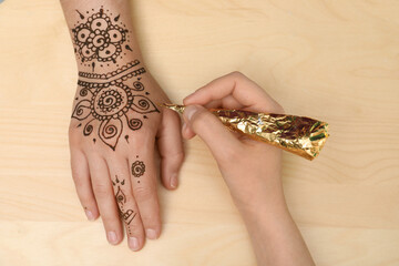 Master making henna tattoo on hand, top view. Traditional mehndi