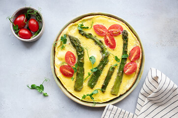 Italian frittata with asparagus, tomatoes and green pea microgreens in ceramic plate. Balanced and tasty morning food. top view