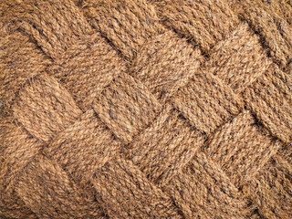 Jute rug close-up. The jute weave is close. A fragment of a large weaving with a rhombus, background, texture. Lint-free carpet.