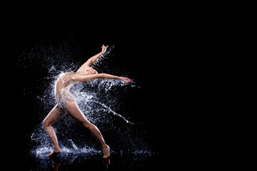 Slender woman in wet sports underwear dancing on surface of water. Ballet dancer is making tricks...