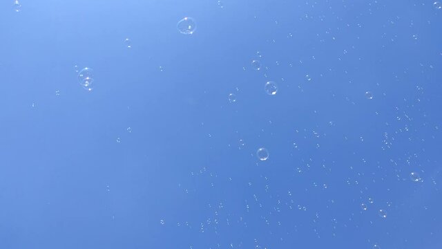 Bright summer sun and soap bubbles fly in the blue sky. Happiness and children's holiday concept.