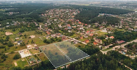 Fotobehang Marked vacant land for construction and sale. The concept of selling land and residential real estate on the land market is an aerial shot with overlay. © Andrii Chagovets