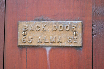 Wooden Door with Old Brass Plate saying 'Back Door'  
