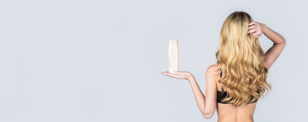 Woman long hair. Woman hold bottle shampoo and conditioner. Woman holding shampoo bottle. Beautiful blonde girl with a bottle of shampoos in hands. Girl with shiny and long hair