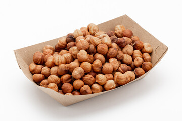 Peeled hazelnuts in a cardboard box on white, angled view. Template for designers