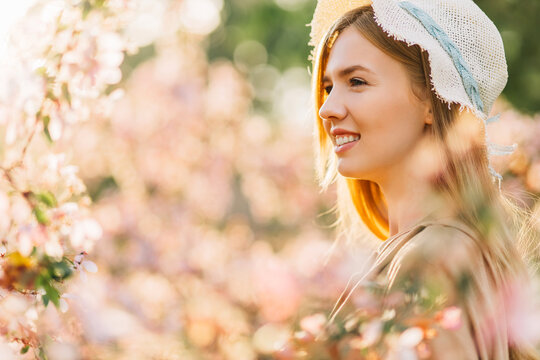 romantic image of tender young woman, in hat, happy smiling woman with spring flowers in the garden, spring concept