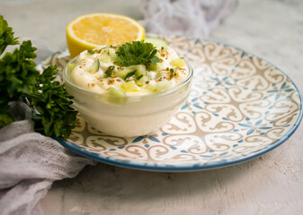 tzatziki sauce, lemon, cucumber on concrete background