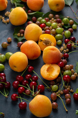 Fresh apricots and cherries on dark surface, summer fruits