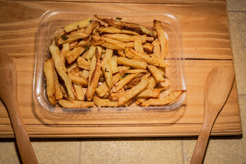 Golden classic fries make an incredible appetizer in a plastic tray for distribution as a side dish or to eat alone. Mediterranean cuisine photography for magazine or online delivery menu concept.
