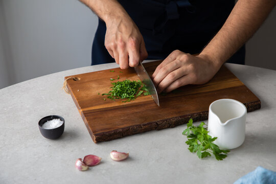 Crop man chopping herbs on table