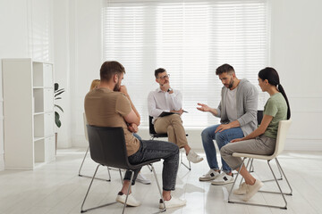 Psychotherapist working with group of drug addicted people at therapy session indoors