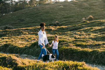 Black woman with kid and dog walking in nature