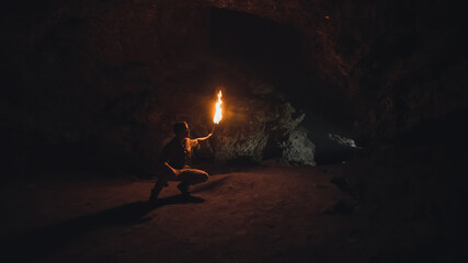 Explorer with burning torch in cave