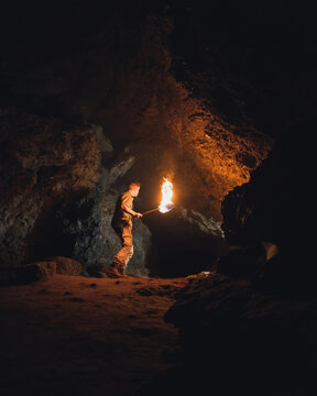 Man with burning fire in dark cave