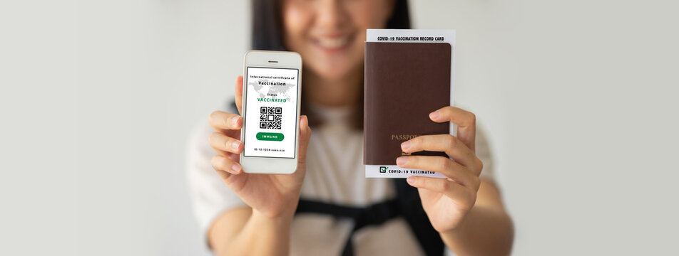 Selective focus, Asian female holding health passport of vaccination certification on smartphone and passport with vaccination label inside at the airport. Travel concept during COVID-19 pandemic.