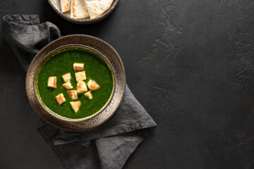 Palak paneer of spinach and cheese on a black background with copy space. Traditional Indian cuisine. View from above.