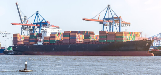 Large container vessel, harbour facilities and famous swimming statute in Övelgönne in Hamburg,...