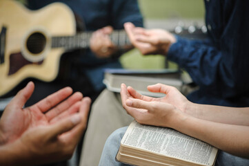 Christian family groups holding hands praying with Holy Bible. and play guitar to sing worship thanksgiving praise and seek the blessings of God with belief. reading Bible and sharing the gospel - obrazy, fototapety, plakaty
