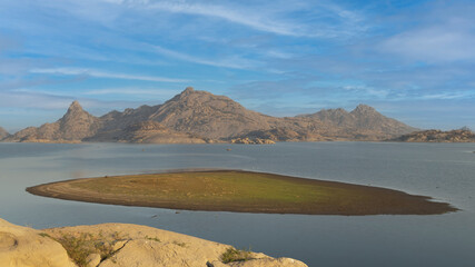 View of a small island in the middle of Jawai dam with clouds and blue sky in the background at...