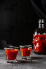 Tomato cocktail in a skull-shaped bottle and glasses. Drink for Halloween party