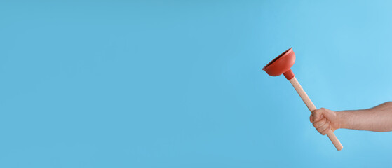 Man holding plunger on turquoise background, closeup. Space for text