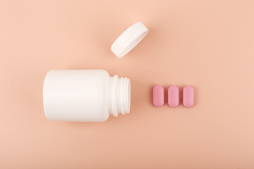 Creative flat lay with white opened medication bottle with pink spilled pills in a row against...